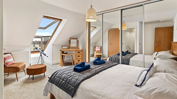 A bedroom with a large bed, a desk, a chair, a telescope, and a wardrobe. - Maes-y-berllan - Close to Village and Beach (Saundersfoot)