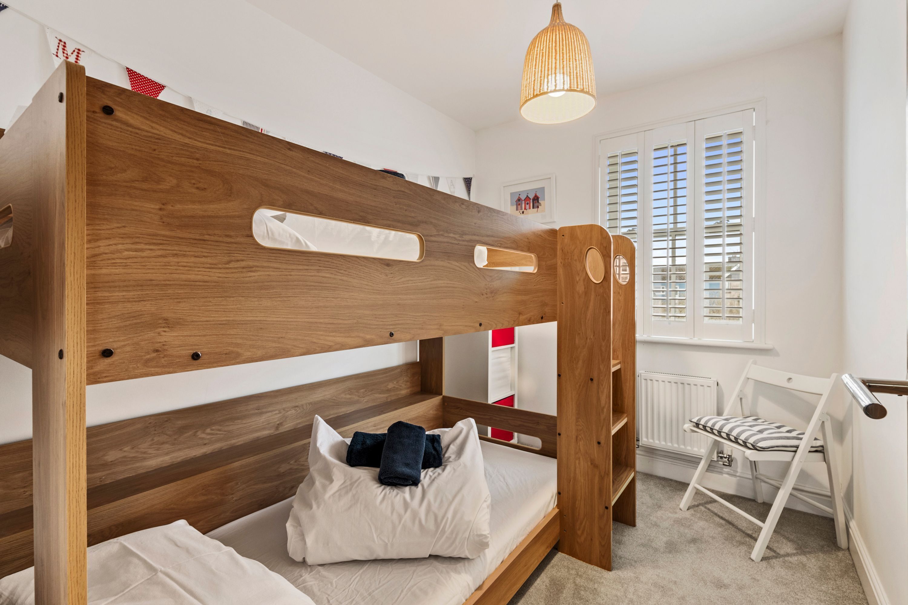 Un lit superposé avec une tête de lit en bois, une table de chevet et une chaise.