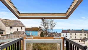 A view from a balcony with a skylight, overlooking a coastal town with houses and a clear sky. - Maes-y-berllan - Close to Village and Beach (Saundersfoot)