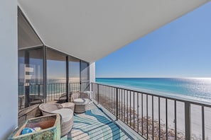 Un balcone con mobili in vimini, un tappeto decorato e vista sull'oceano.