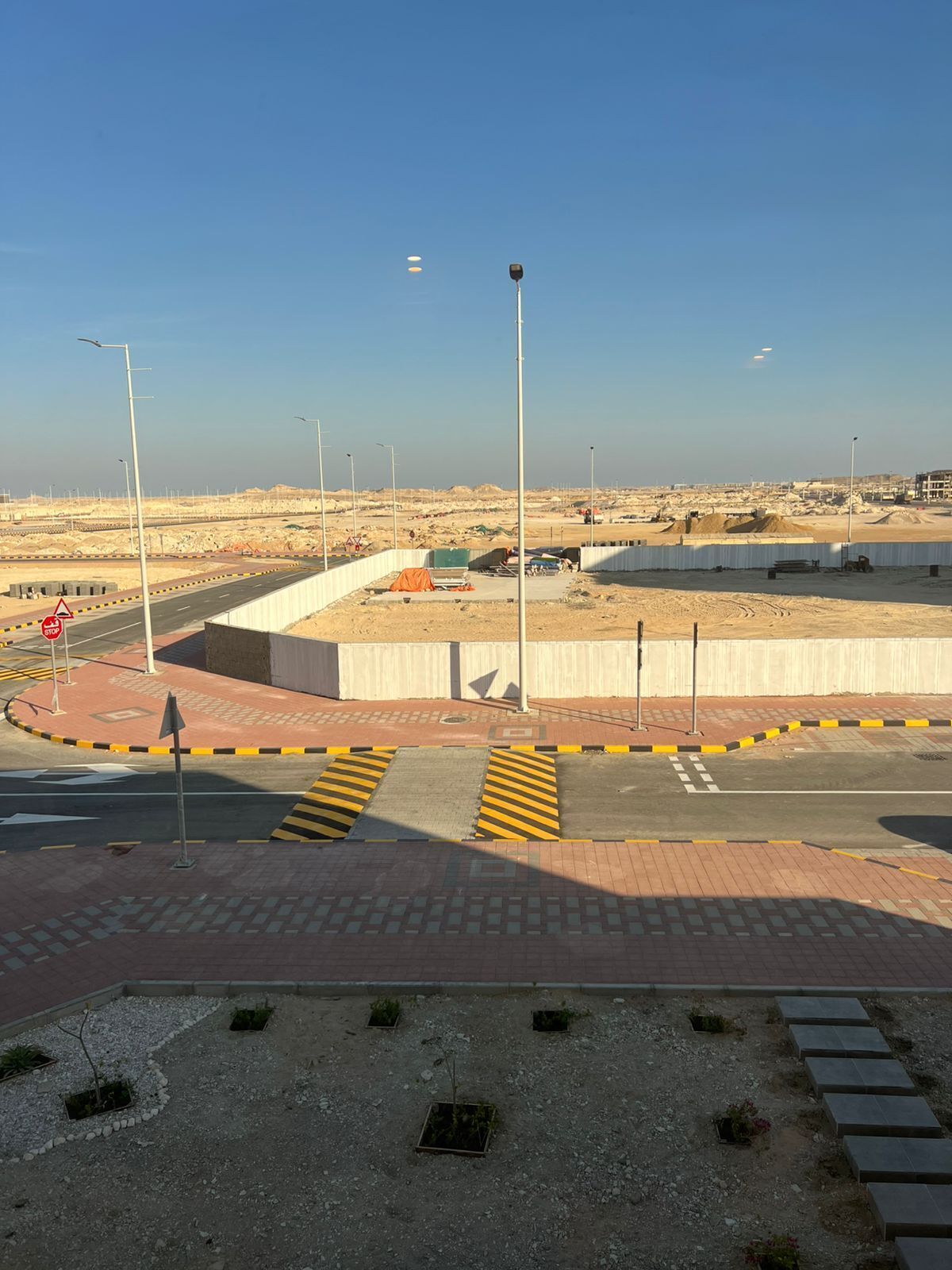 A roundabout with a pedestrian crossing and a road leading to a construction site.