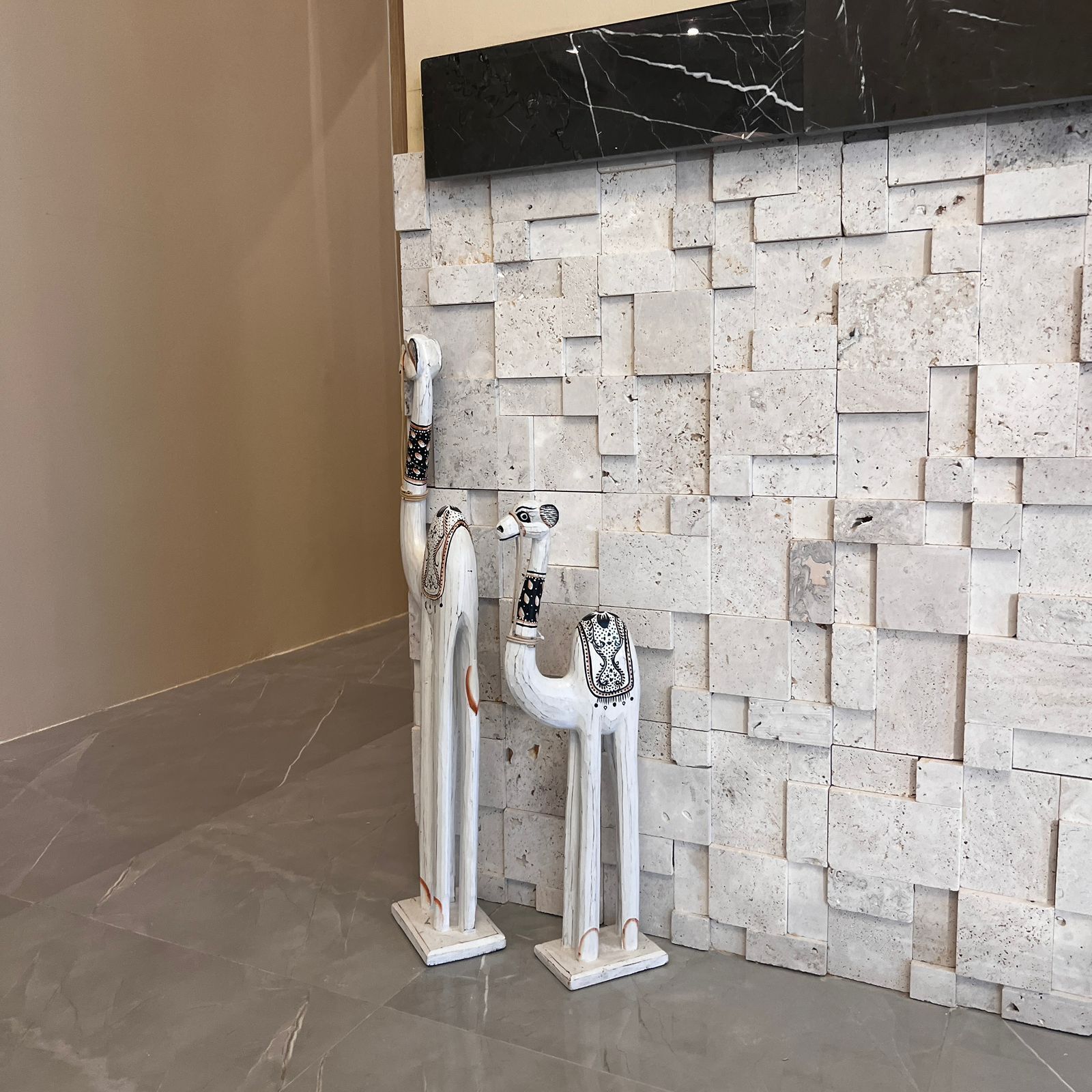 A lobby with a marble wall and two decorative white columns with black patterns.