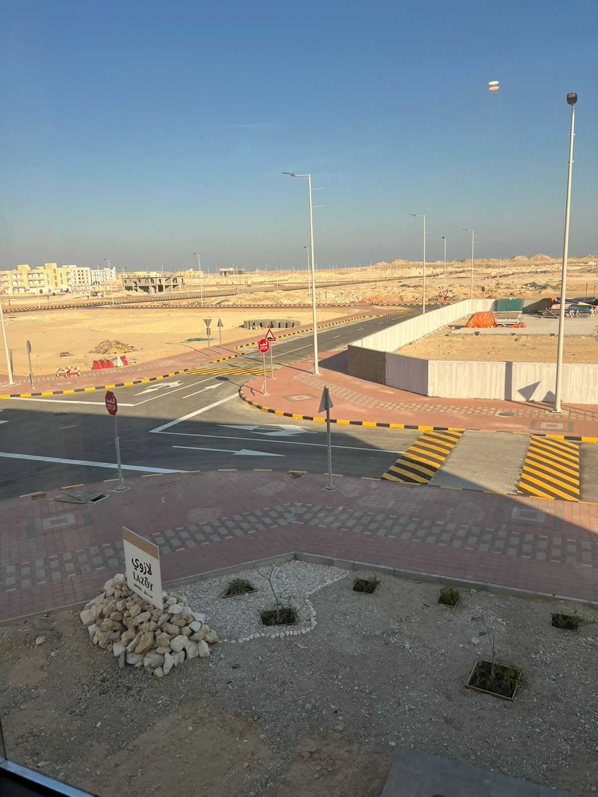 A road intersection with a stop sign, pedestrian crossing, and a sign indicating a roundabout ahead.