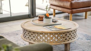 A round wooden table with a tray, a small potted plant, and a remote control. - Tasman Towers 4 - Conveniently located in the CBD (Port Macquarie)