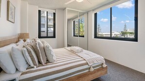 A bedroom with a bed, a ceiling fan, large windows, and a view of the outside. - Tasman Towers 4 - Conveniently located in the CBD (Port Macquarie)