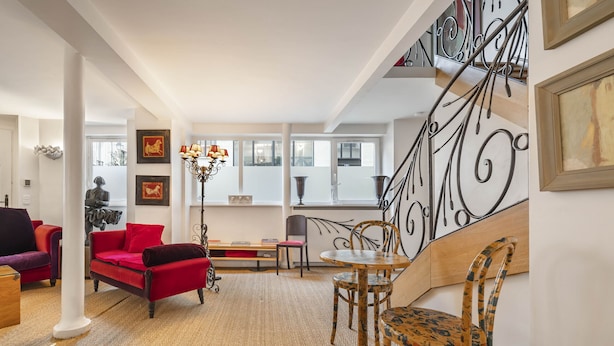 A spacious living room with a red sofa, a wooden dining table, and a staircase with a wrought iron railing. - Ballerine, 3BR/2BA, 6 people (París)