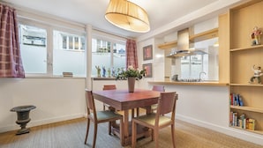 A dining area with a wooden table and chairs, a vase with flowers, a pendant light, and a bookshelf with books and figurines. - Ballerine, 3BR/2BA, 6 people (París)