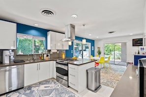 Una cocina moderna con armarios blancos, una estufa de acero inoxidable y una isla grande con asientos.