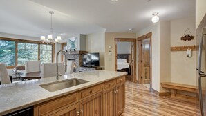 A modern kitchen with a large island, wooden cabinets, and a built-in dishwasher. - Bright, Mountain Modern Breckenridge Condo 1 Bedroom Condo (Breckenridge)