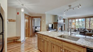 A spacious kitchen with wooden cabinets, a granite countertop, and a large window providing a view of the outdoors. - Cozy Ski Chalet With Large Balcony 1 Bedroom Condo (Breckenridge)