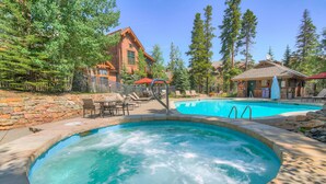 Un jacuzzi y un área de piscina con sillones reclinables y una pared de piedra.