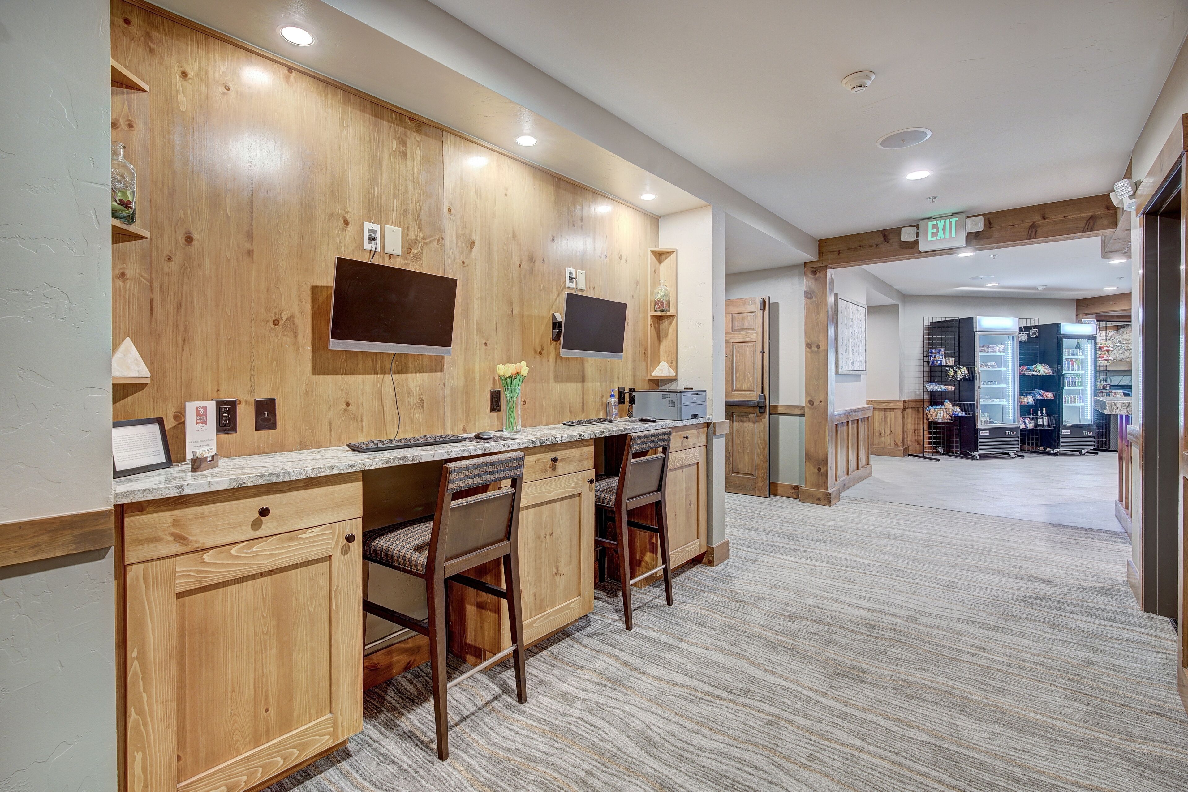 A modern kitchen with wooden cabinetry, a marble countertop, and a built-in TV.