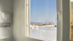 Et værelse med et vindue der kigger ud på en strand og bygninger, dekoreret med en hjerteform, og et skilt med teksten 'LOVE'.