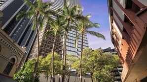 A tall modern building with a glass facade and palm trees in front. - Chic Dt Honolulu Executive Condo 1 Bedroom Condo (Honolulu)
