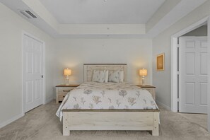 Un dormitorio con cama, lámparas de noche, una puerta y un cuadro colgado en la pared.