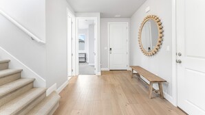 A hallway with a wooden staircase, a wooden bench, and a round mirror on the wall. - Desert Rose Hideaway 5 Bedroom Home (Washington)
