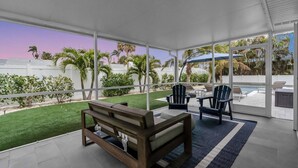Un patio techado al aire libre con un banco de madera, dos sillas tipo Adirondack y una mesa.