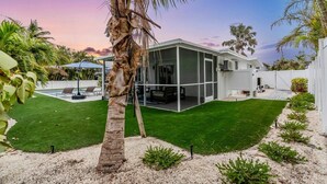 Una casa moderna con un porche acristalado, césped bien cuidado y piscina.