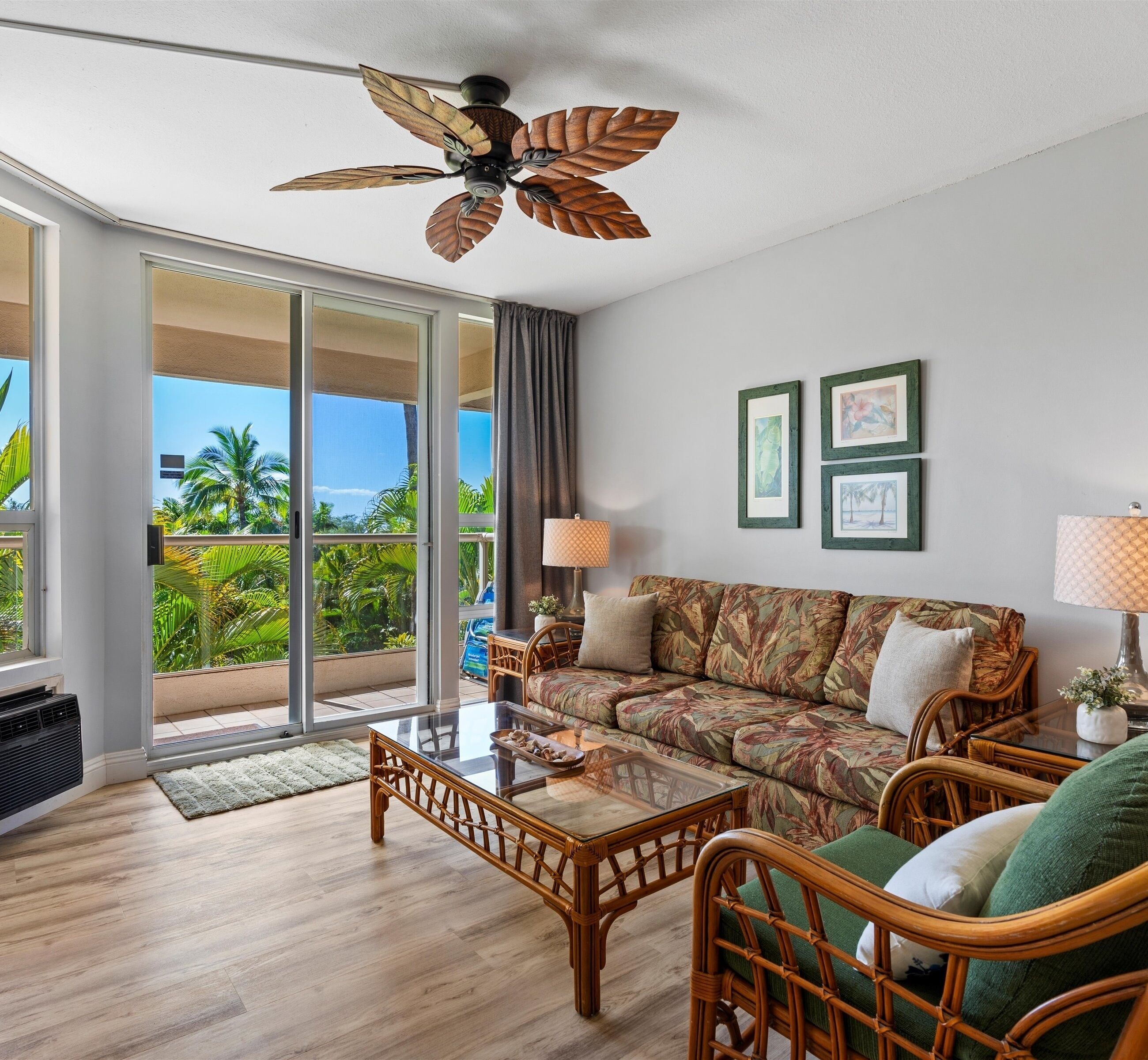 A spacious living room with a large window, a ceiling fan, a sofa, a coffee table, and a view of the outdoors.