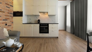 Een moderne keuken met witte kasten, een bakstenen muur en een houten vloer.