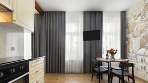 Een moderne keuken met een zwart fornuis, beige keukenkastjes en een eethoek met een tafel en stoelen.