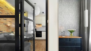 Een moderne keuken met witte kasten, een zwarte oven en een houten vloer.