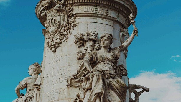 A detailed stone monument with inscriptions and sculptures, including a figure holding a torch and another with a laurel wreath. - Elegant Apartment for 4 People (Paris)