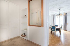 Una habitación amplia con zona de comedor, un espejo grande y suelo de madera.