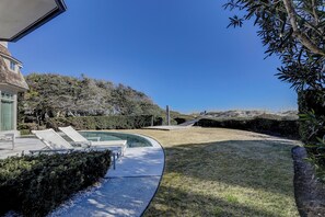 Ein modernes Haus mit Pool, einer Terrasse und Liegestühlen sowie einem gepflegten Rasen.