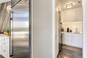 Una cocina moderna con electrodomésticos de acero inoxidable, armarios blancos y un salpicadero de mármol.