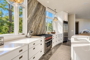 A modern kitchen with white cabinetry, a gas stove, and a stainless steel refrigerator.