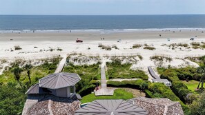 Blick auf einen Strand mit einem Weg, der zu einem Gebäude mit einem geneigten Dach führt.