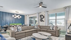 Een moderne woonkamer met een hoekbank, een glazen salontafel en een eethoek met een glazen tafel en stoelen.