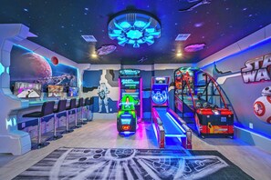 Une salle d’arcade sur le thème de Star Wars, avec des néons, une borne d’arcade centrale et un mur décoré aux couleurs de Star Wars.