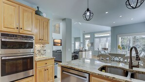 A modern kitchen with stainless steel appliances, wooden cabinets, and a large island with a sink.