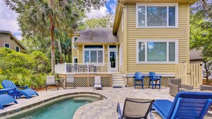 A two-story house with a pool, outdoor seating, and a fenced deck.