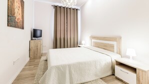 A modern bedroom with a bed, bedside table, lamp, and a television on a cabinet. - Minsk Apartment Lux on Nezavisimosti 43 (Minsk)