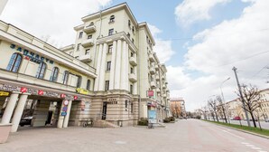 A multi-story building with a classical architectural style, featuring a prominent entrance with a canopy and signage for various businesses. - Minsk Apartment Lux on Nezavisimosti 43 (Minsk)