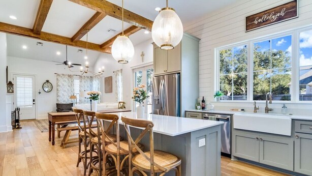 Una cocina amplia con una isla grande, sillas de madera e iluminación colgante.