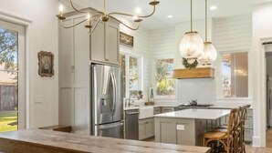 Una cocina amplia con una isla grande, vigas de madera e iluminación colgante.