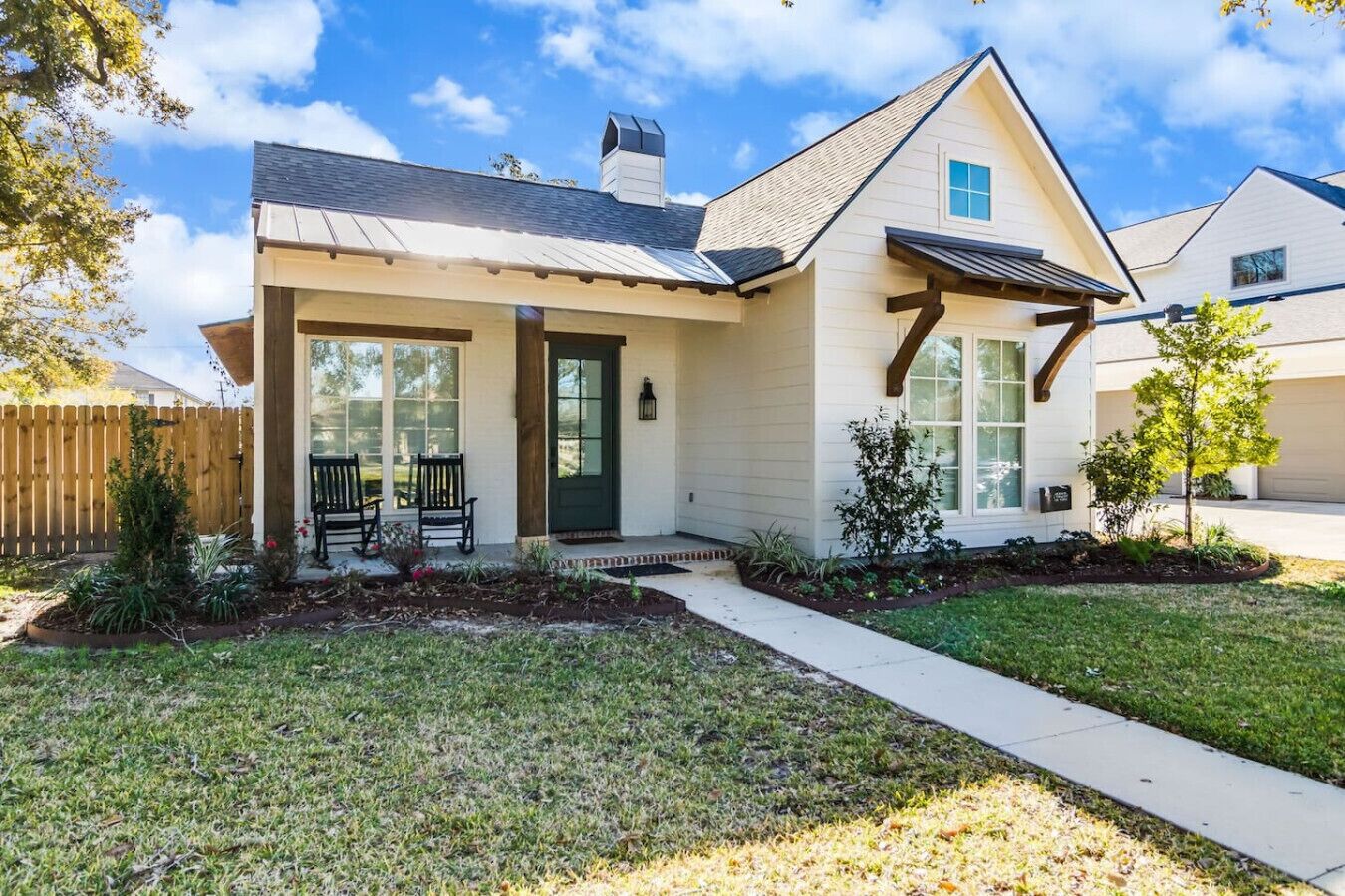 A single-story house with a front porch, a covered entryway, and a small garden area.