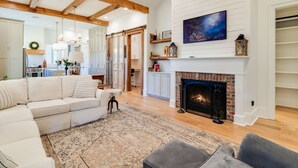Un salón amplio con chimenea, un sofá grande y un comedor al fondo.