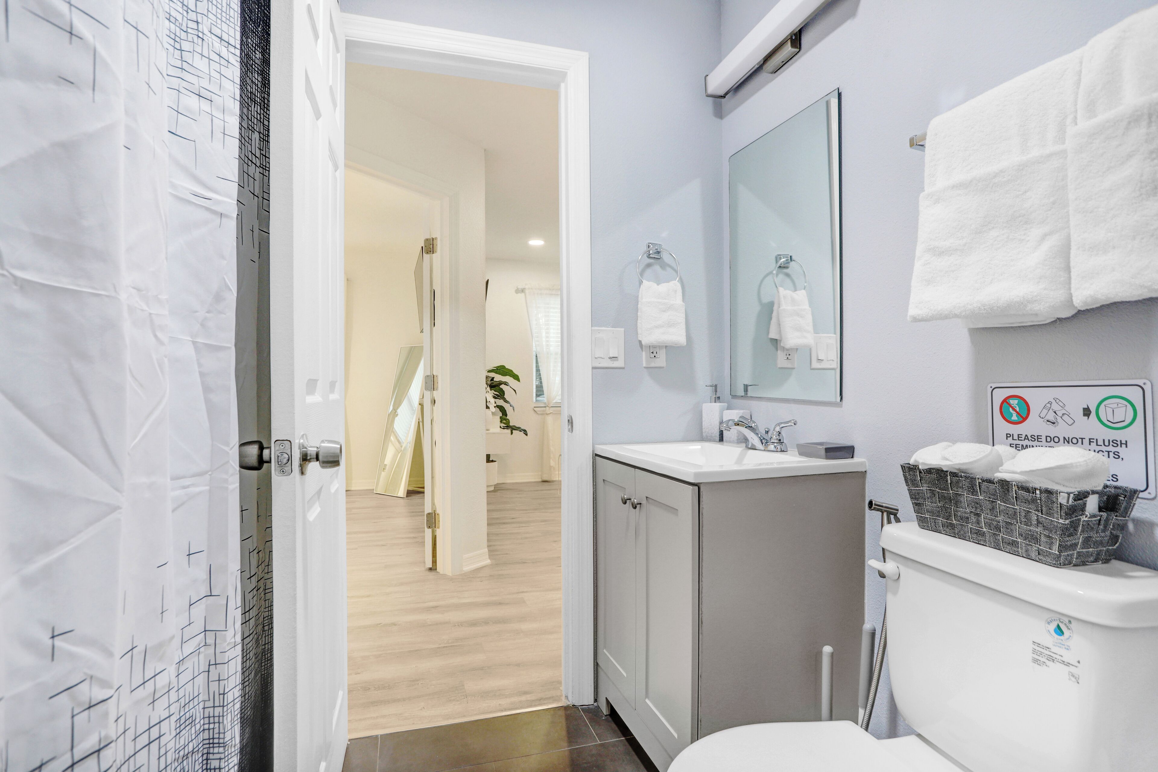 Et moderne badeværelse med toilet, håndvask og bruseområde.