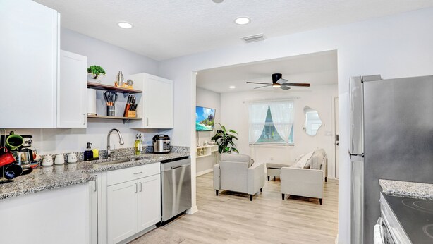 A modern kitchen with white cabinets, a stainless steel refrigerator, and a granite countertop.