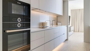 A modern kitchen with a Bosch oven, white cabinetry, and a sleek countertop. - RJS Savoy Monumentalis (Funchal)