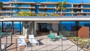 A modern hotel with a glass facade, outdoor seating area, and a view of the ocean. - RJS Savoy Monumentalis (Funchal)