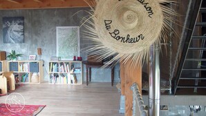 A spacious room with a wooden ceiling, a bookshelf, a map, and a woven basket with text. - Self-catering ecogîte in the heart of the forest at La Chapelle-en-Vercors (La Chapelle-en-Vercors)