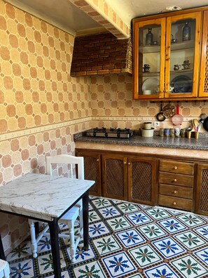 Enjoy cooking in this kitchen with a gas stove, wooden cabinets, and a marble-top table.