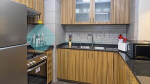 A kitchen with wooden cabinets, a stainless steel refrigerator, a microwave, and a sink. - Bloomfields Superior1BR Ajwan Soul Beach (Abu Dhabi)