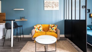 A compact living space with a sofa, a coffee table, a desk, and a bed. - Le studio epure du commandant (Évreux)